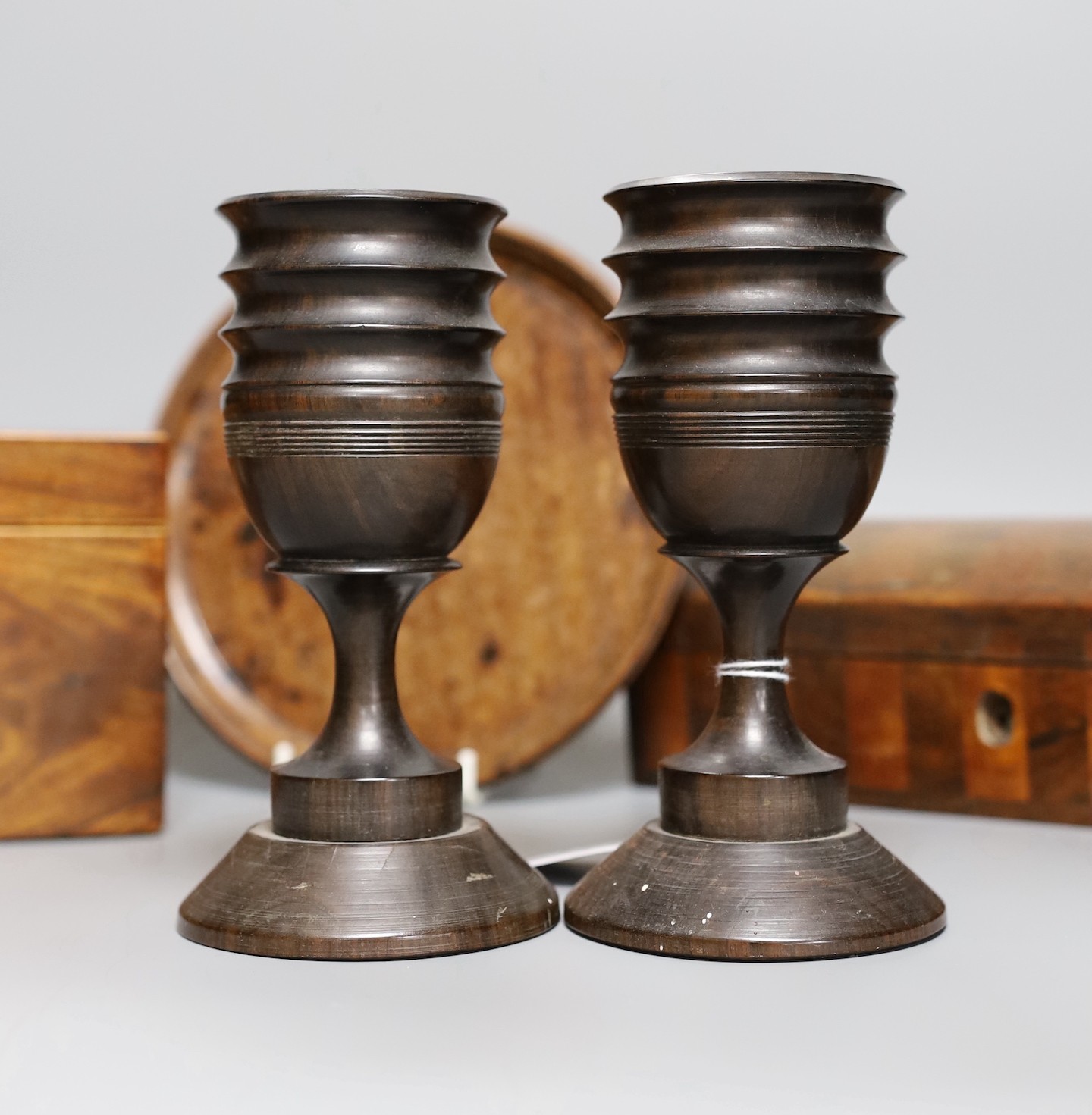 A George III inlaid mahogany tea caddy, a Victorian satinwood and rosewood domed topped glove box, a burr wood circular tray, a George III inlaid mahogany domed topped easel mirror and a pair of turned hardwood cups